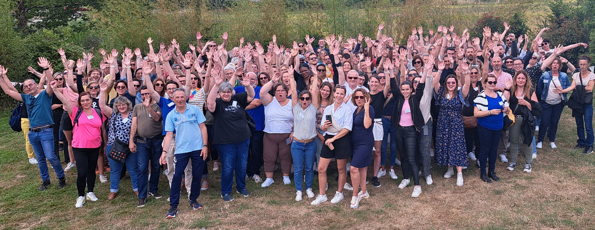 Photo des collaborateurs de Silène prise lors de la journée du personnel en juin 2023 dans le jardin de la salle "C'est ici" à Saint-Nazaire. Photo prise de haut, les collaborateurs ont le sourire et lève les bras pour certains.