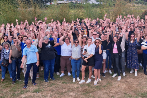 Photo des collaborateurs de Silène prise lors de la journée du personnel en juin 2023 dans le jardin de la salle "C'est ici" à Saint-Nazaire. Photo prise de haut, les collaborateurs ont le sourire et lève les bras pour certains.