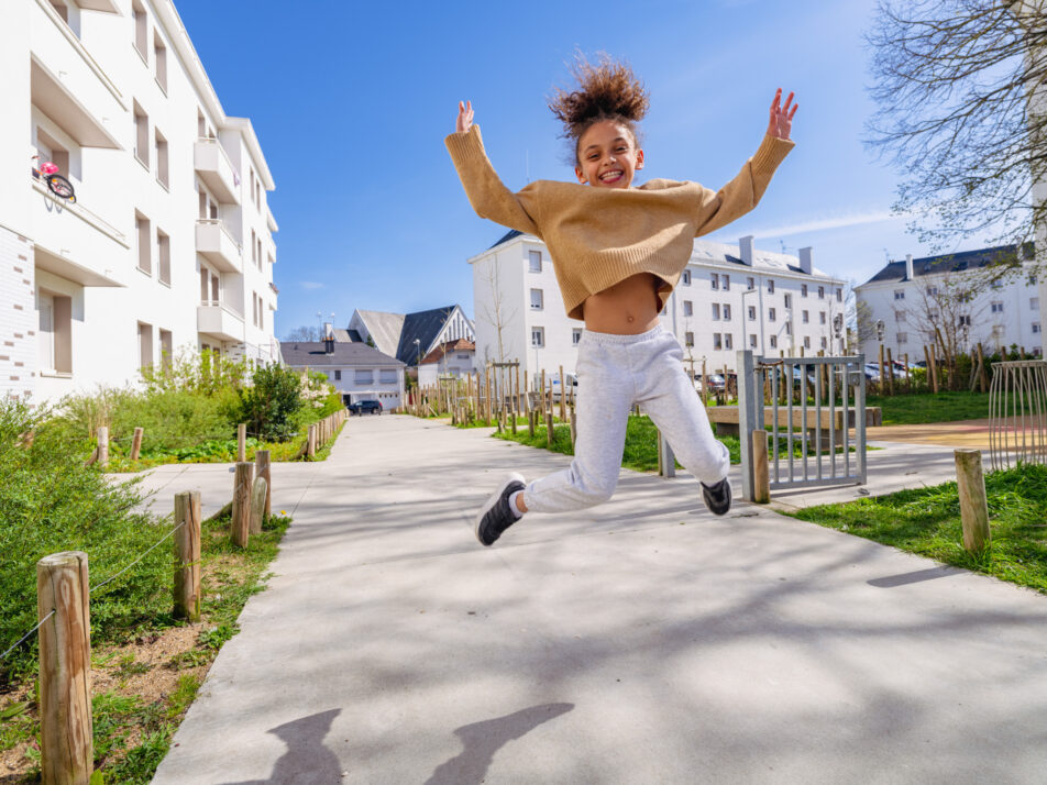 Photographie d'une petite fille qui saute en l'air devant la résidence cardurand.