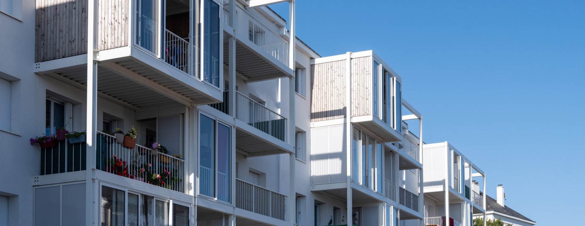 Photographie de la résidence Jules Guesde, réhabilitée. Avec un focus sur les nouvelles loggias pour chaque appartement. A l'arrière plan, un grand ciel bleu.