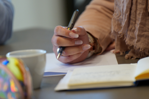 Photo en gros plan de la main d'une femme qui est en train de prendre des notes.