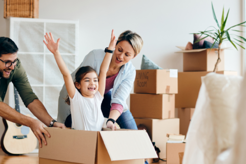 photo représentant une famille dans son salon qui emménage dans leur nouvelle maison : parents et une petite fille dans un carton.