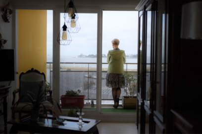 Femme contemplant la vue sur la mer depuis le balcon de son appartement. - Agrandir l'image, fenêtre modale